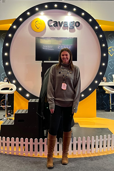 Person standing in front of a lit Cavago display with a circular logo and white